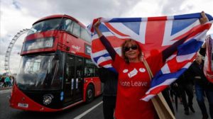 A campaigner wearing a Vote Leave t-shirt and holding a British Union Flag also known as a Union Jack stands on a Westminster Bridge near the Houses of Parliament in London U K Wednesday June 15 2016 The Brexit battle took to London s River Thames as boats supporting the Leave and Remain campaigns jostled for space while Irish rock star Bob Geldof harangued U K Independence Party leader Nigel Farage using a sound system Photographer Luke MacGregor Bloomberg via Getty Images